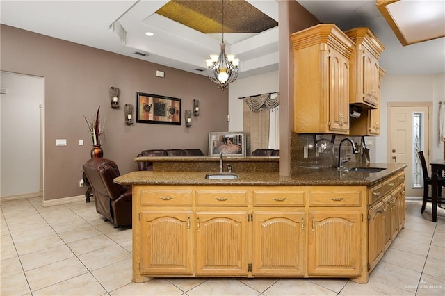 kitchen with sink, kitchen peninsula, light tile patterned floors, and a tray ceiling