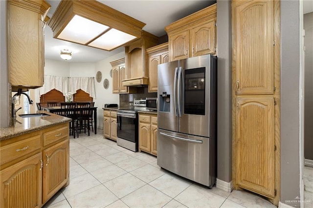 kitchen with premium range hood, appliances with stainless steel finishes, light brown cabinetry, and sink