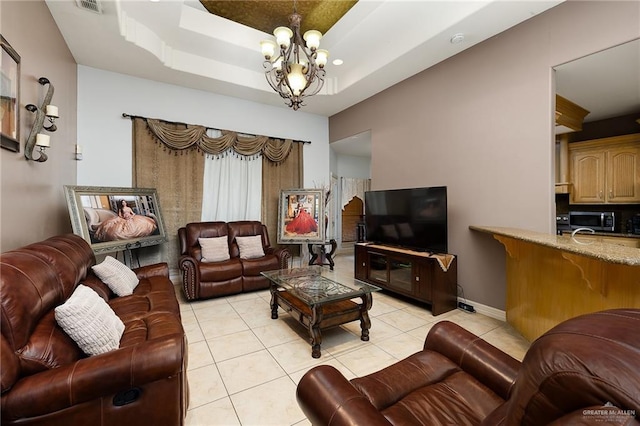 living room featuring an inviting chandelier, a tray ceiling, and light tile patterned flooring