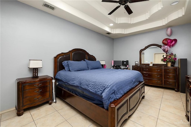 tiled bedroom with ceiling fan and a tray ceiling