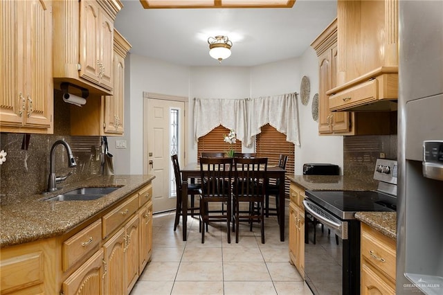 kitchen featuring dark stone countertops, sink, stainless steel appliances, and light brown cabinets