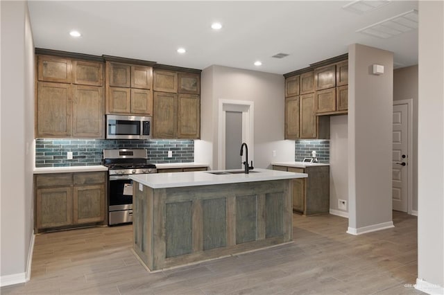 8329 N 35th St, Mcallen, TX 78504 - kitchen featuring appliances with stainless steel finishes, backsplash, an island with sink, light countertops, and light wood finished floors