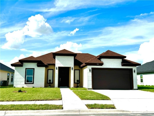 prairie-style home featuring cooling unit, a garage, and a front lawn