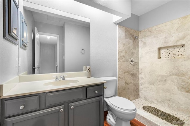 bathroom featuring vanity, toilet, and a tile shower