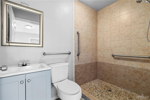 bathroom featuring vanity, tiled shower, and toilet