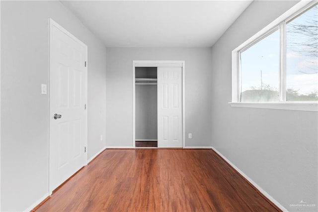 unfurnished bedroom with hardwood / wood-style flooring and a closet