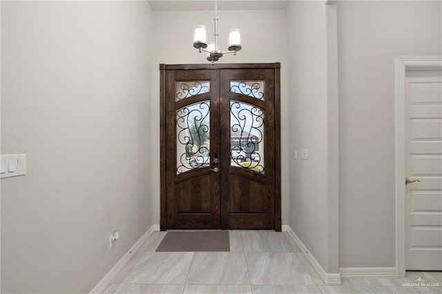 entryway with baseboards, a chandelier, and french doors