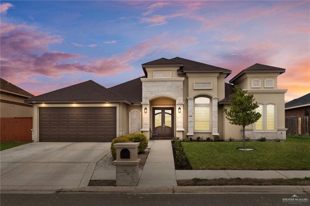 view of front of home featuring a garage, driveway, fence, french doors, and a front lawn