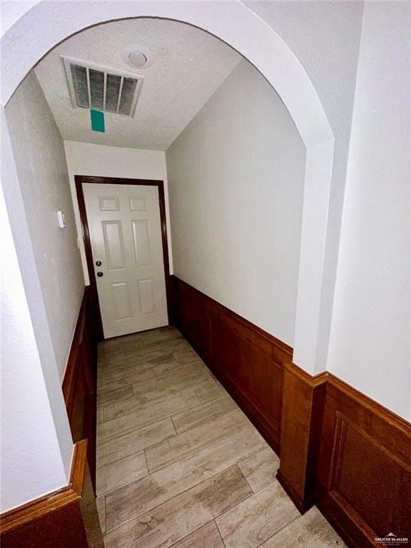 corridor featuring light hardwood / wood-style floors and a textured ceiling