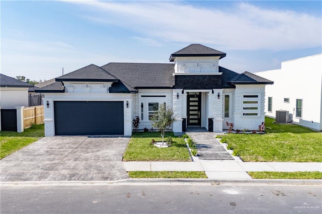 view of front facade with concrete driveway, central air condition unit, an attached garage, and a front lawn