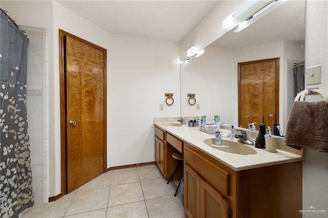 full bathroom featuring double vanity, baseboards, a sink, and tile patterned floors