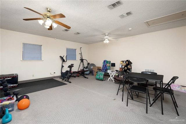 workout room featuring a ceiling fan, carpet, visible vents, and a textured ceiling