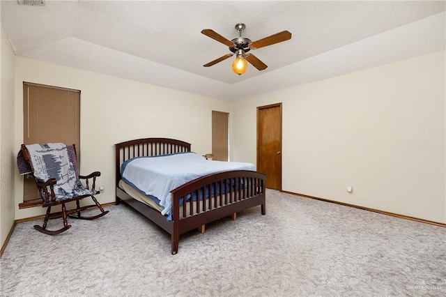 carpeted bedroom with visible vents, a tray ceiling, a ceiling fan, and baseboards