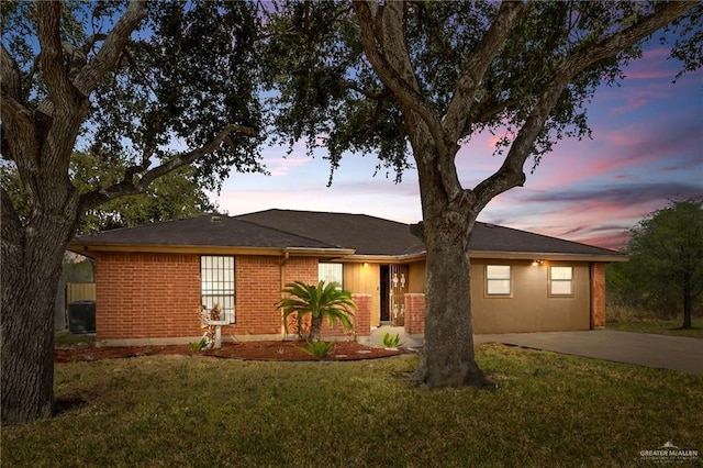 single story home featuring concrete driveway, brick siding, and a front yard