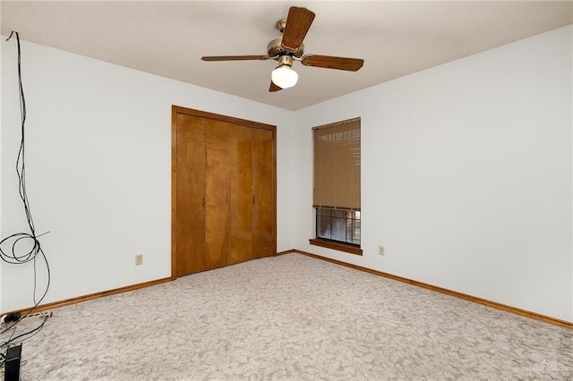 unfurnished bedroom featuring a closet, carpet, a ceiling fan, and baseboards