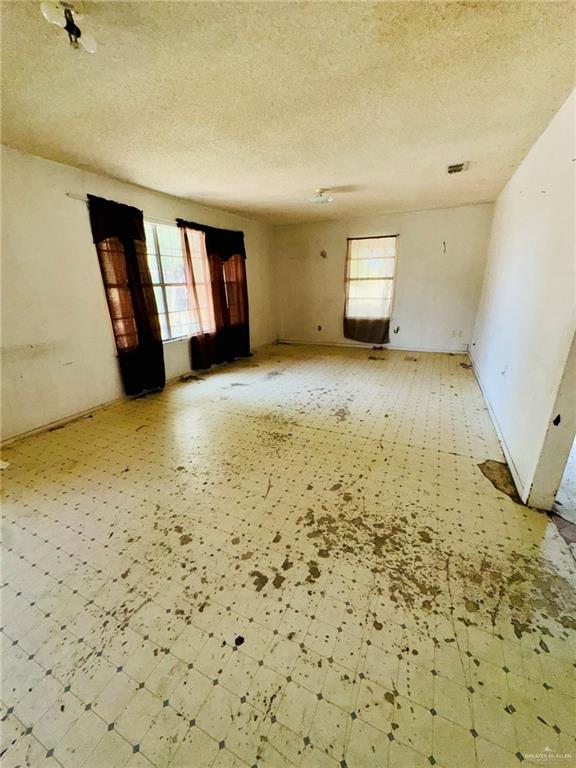 unfurnished room featuring a textured ceiling and a healthy amount of sunlight