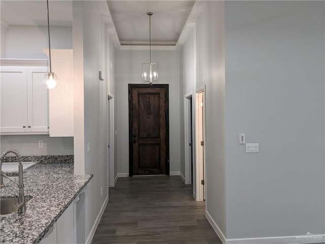 hallway with dark wood-type flooring, a sink, a high ceiling, and baseboards