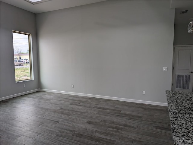 unfurnished room featuring dark wood-type flooring, visible vents, and baseboards