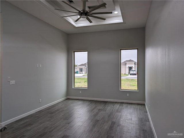 spare room with ceiling fan, baseboards, a tray ceiling, and dark wood finished floors