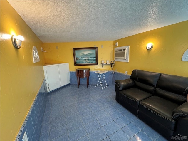 tiled living room featuring a wall mounted air conditioner and a textured ceiling