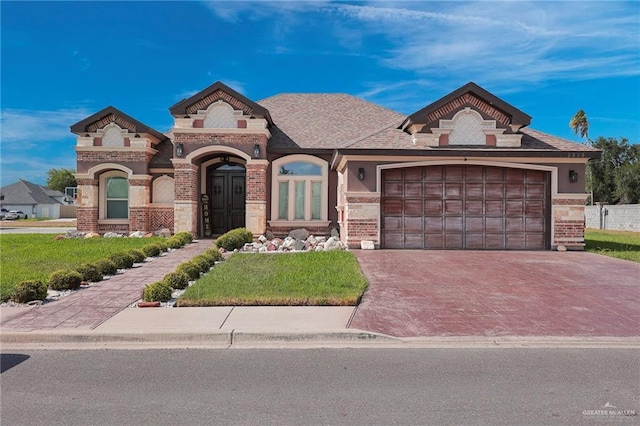 2000 Shelby St, Mission, TX 78572 - french country inspired facade featuring brick siding, decorative driveway, a garage, and a front lawn