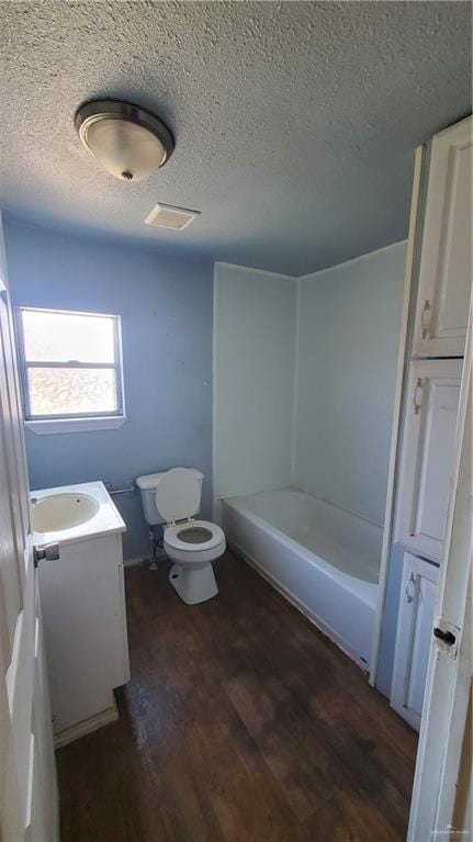 full bathroom featuring vanity, washtub / shower combination, hardwood / wood-style flooring, toilet, and a textured ceiling