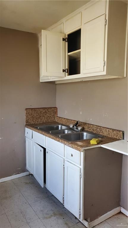 601 E Ricky Crossland Ave, Elsa, TX 78543 - kitchen with a sink, white cabinets, and baseboards