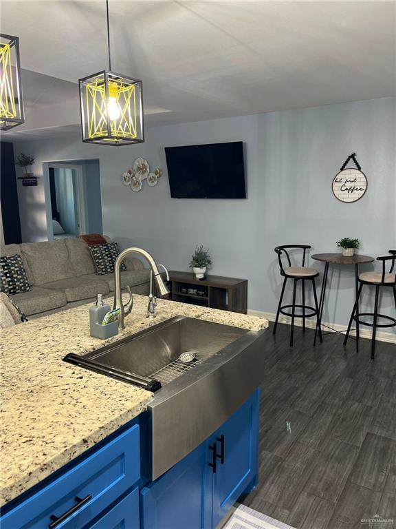 442 La Villita Dr, Donna, TX 78537 - kitchen featuring blue cabinets, a sink, light stone countertops, open floor plan, and dark wood-style flooring