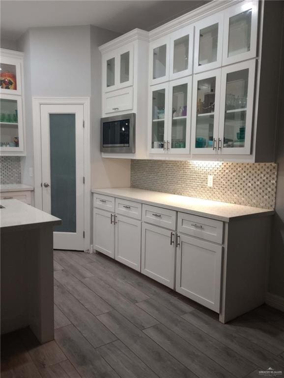 kitchen with stainless steel microwave, light countertops, white cabinets, and dark wood finished floors