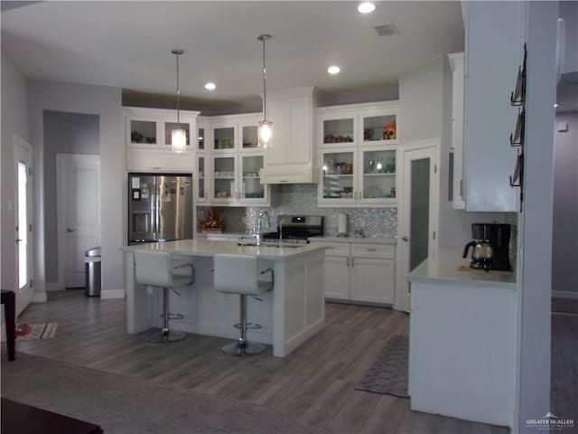 kitchen featuring pendant lighting, a kitchen island with sink, white cabinets, dark hardwood / wood-style floors, and appliances with stainless steel finishes