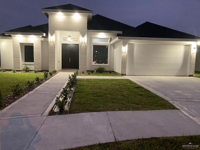 view of front of house featuring a garage, driveway, a front lawn, and stucco siding