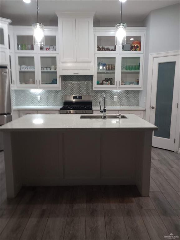 kitchen featuring white cabinetry, a sink, light countertops, gas stove, and an island with sink