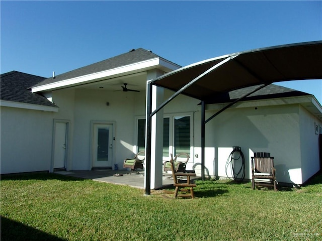 rear view of house featuring ceiling fan, a yard, and a patio