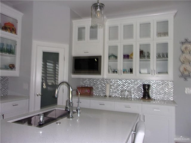 kitchen featuring decorative backsplash, sink, white cabinets, and decorative light fixtures