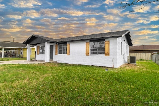 view of front of home featuring central AC, a patio area, and a yard