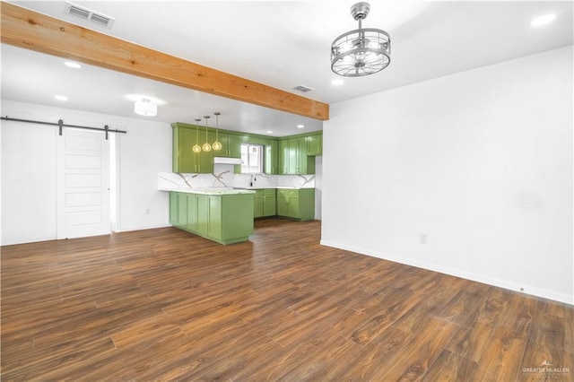 kitchen featuring backsplash, dark hardwood / wood-style floors, a barn door, green cabinets, and hanging light fixtures