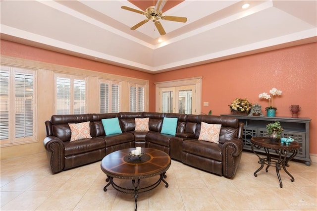 tiled living room with a tray ceiling and ceiling fan