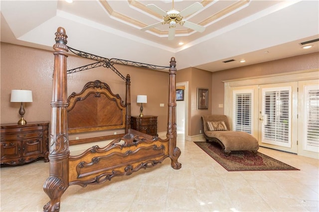 bedroom featuring ceiling fan, access to exterior, and a tray ceiling