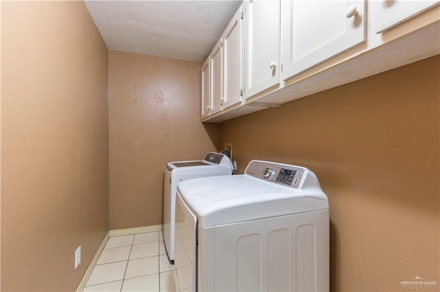 laundry room featuring cabinets, independent washer and dryer, a textured ceiling, and light tile patterned flooring