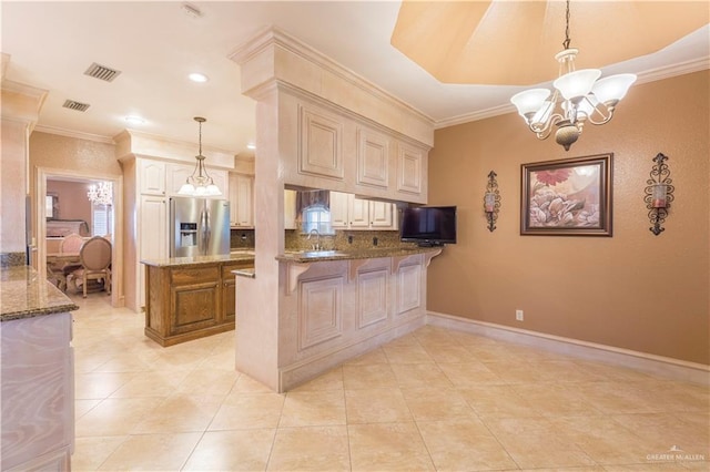 kitchen featuring kitchen peninsula, stainless steel fridge, decorative light fixtures, dark stone countertops, and a breakfast bar area