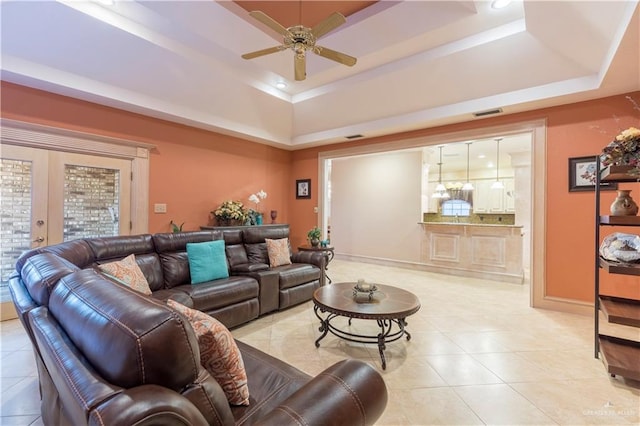 living room featuring a tray ceiling, ceiling fan, french doors, and light tile patterned floors