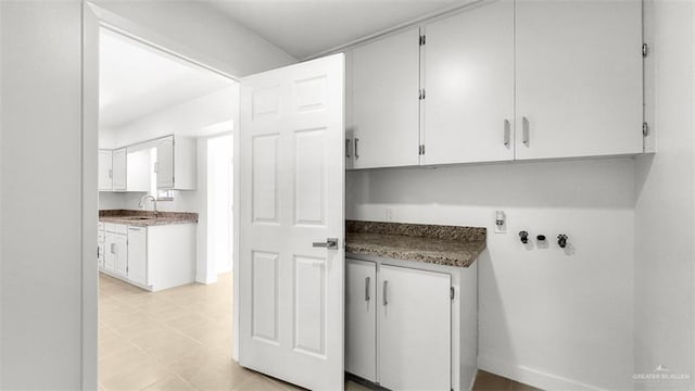 clothes washing area with cabinet space and a sink