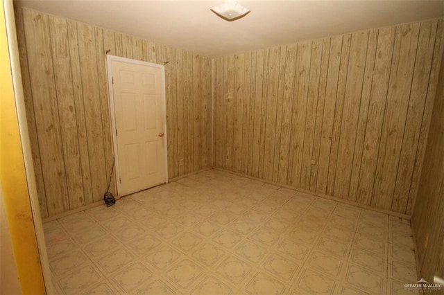 unfurnished room featuring wooden walls and tile patterned floors