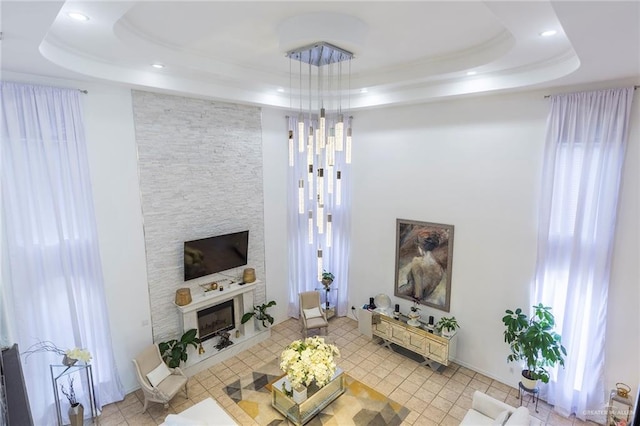 tiled living room with a raised ceiling and a fireplace