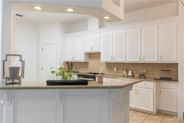 kitchen featuring backsplash, gas range, light stone countertops, and white cabinets