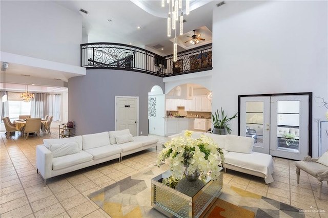 living room featuring ceiling fan, a towering ceiling, and french doors