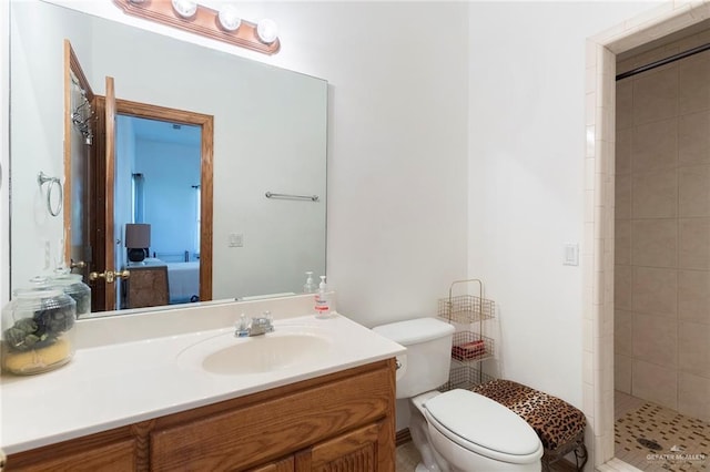 bathroom with a tile shower, vanity, and toilet