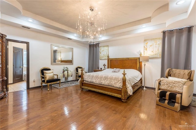 bedroom featuring a chandelier, wood-type flooring, and a tray ceiling