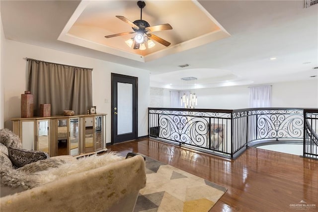 interior space with hardwood / wood-style floors, ceiling fan, and a tray ceiling