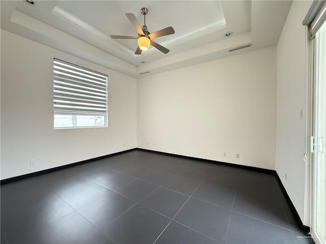 empty room with a tray ceiling, visible vents, and baseboards